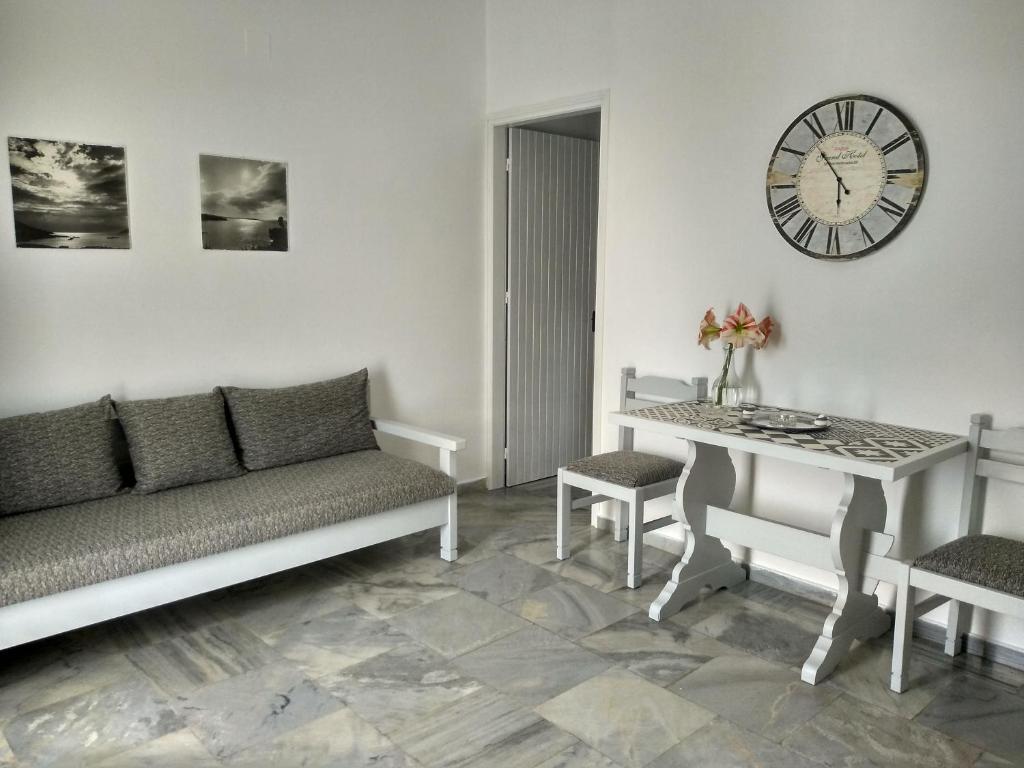 a living room with a couch and a clock on the wall at Galaxy Apartments in Aliki