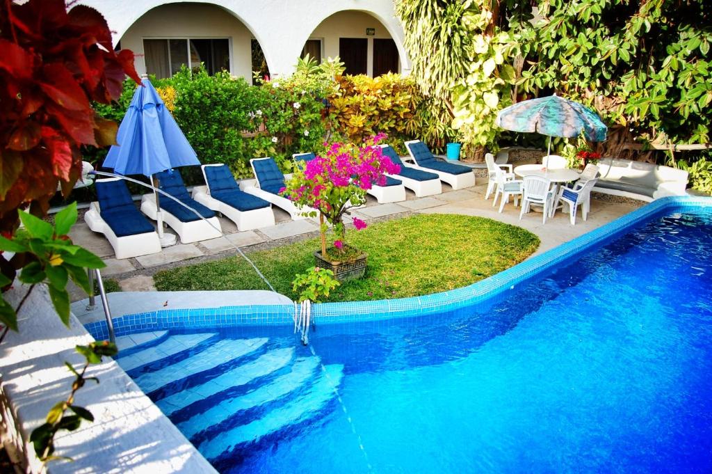 uma piscina com cadeiras, uma mesa e um guarda-sol em Hotel Delfin em Barra de Navidad