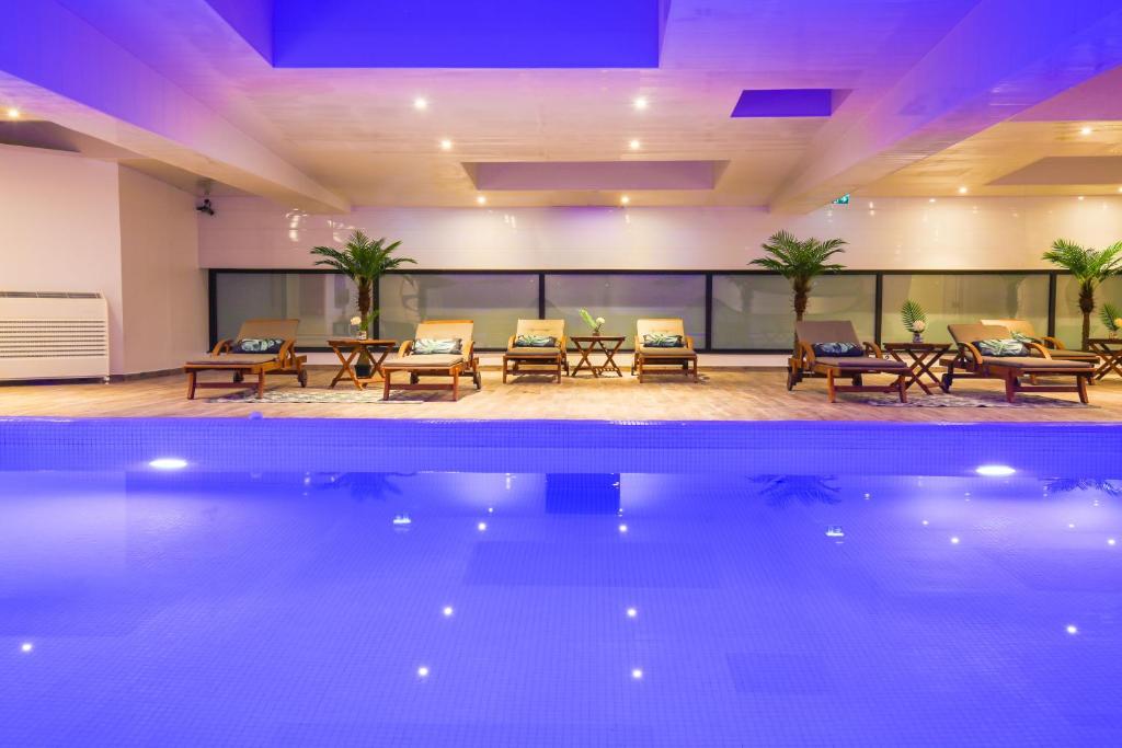 a pool in a hotel with tables and chairs at Zenia Hotel & Spa in Cambrai