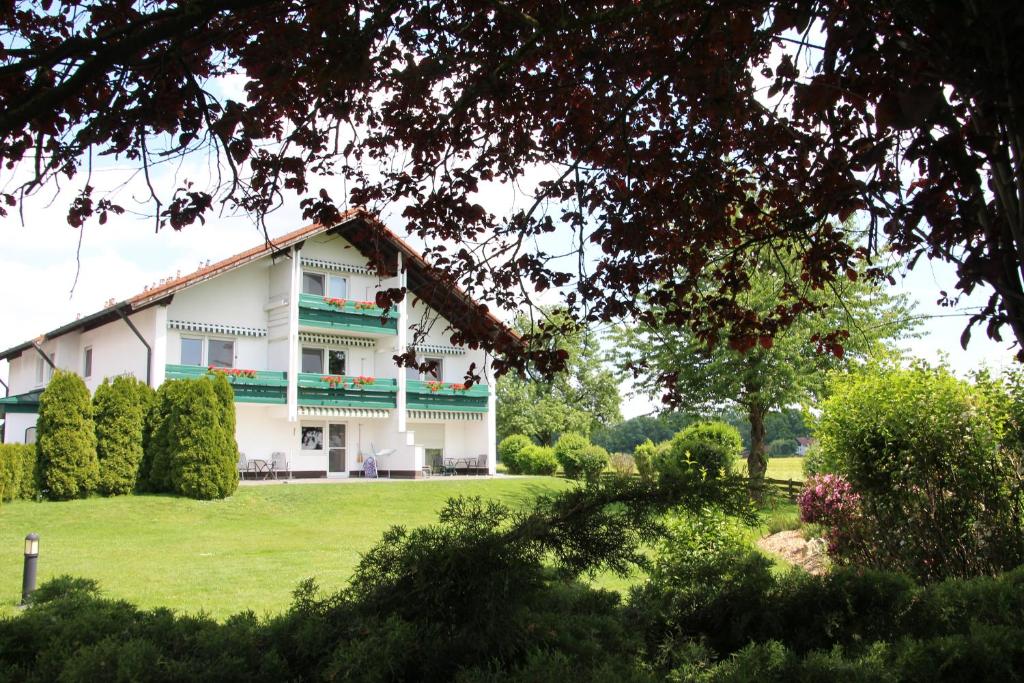 uma grande casa branca com um jardim verde em Aparthotel Naturidyll - Wieserhof em Bad Füssing