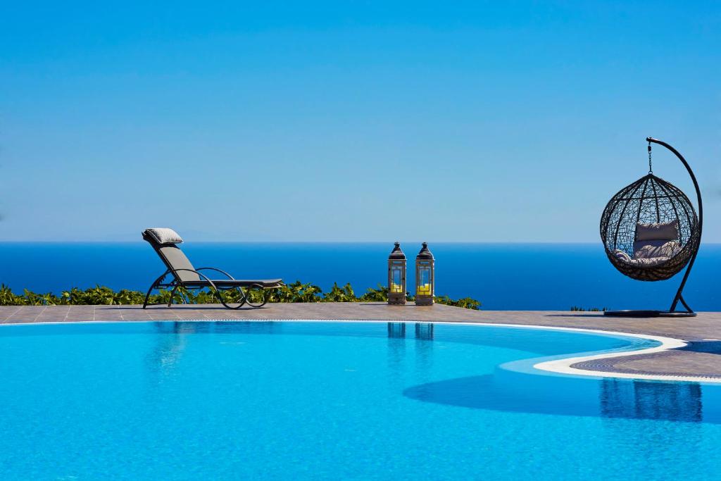une piscine avec une balançoire et l'océan en arrière-plan dans l'établissement Golden East, à Imerovigli