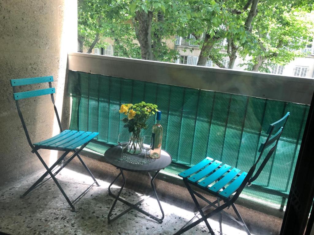 2 sillas y una mesa con un jarrón de flores en el balcón en Aix Homes en Aix-en-Provence