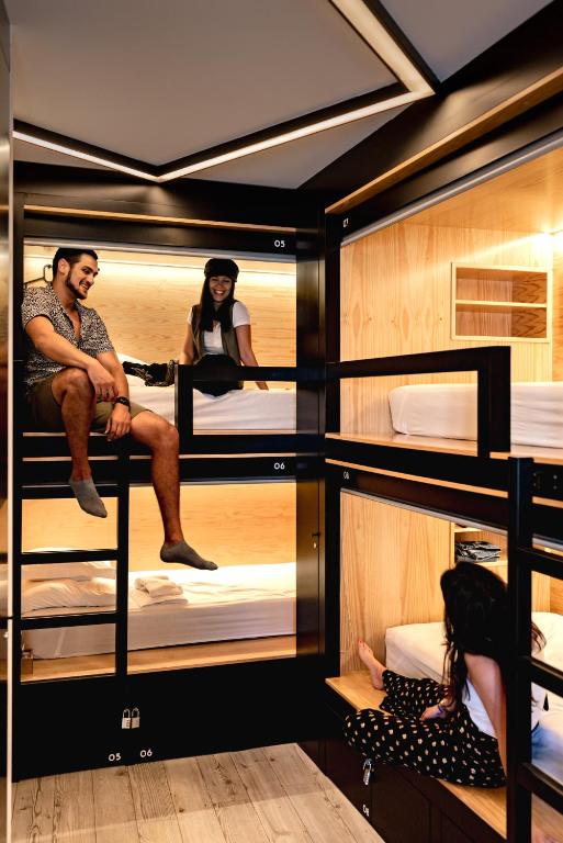 a group of people sitting on top of bunk beds at GiG Capsule Hostel in Ericeira