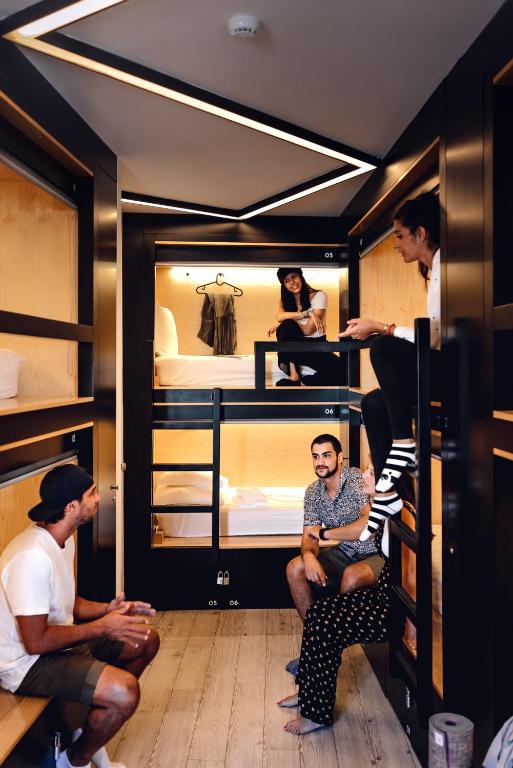 a group of people sitting in a room with bunk beds at GiG Capsule Hostel in Ericeira