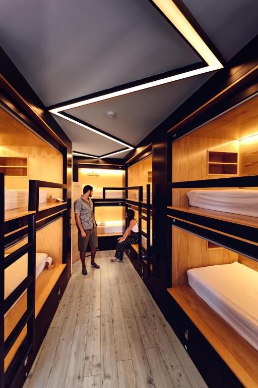 two people standing in a room with bunk beds at GiG Capsule Hostel in Ericeira