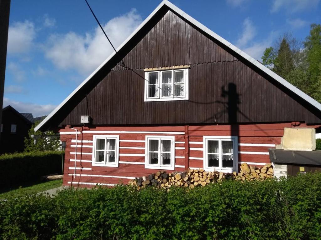 ein rotes Haus mit schwarzem Dach und weißen Fenstern in der Unterkunft Chata Azalka in Albrechtice v Jizerských horách