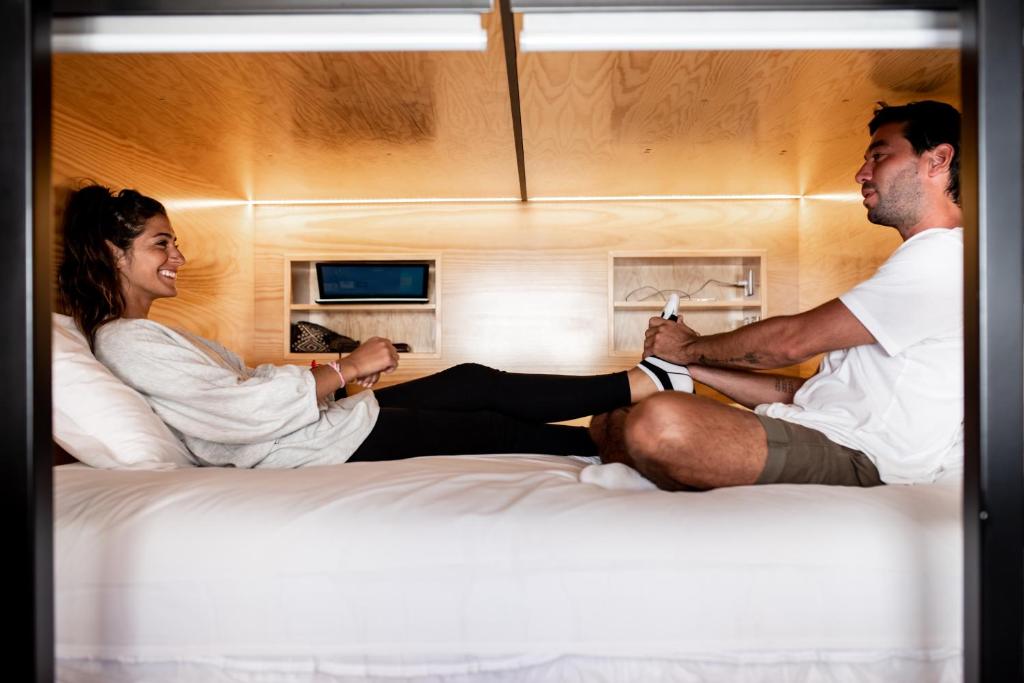 a man and a woman sitting on a bed at GiG Capsule Hostel in Ericeira