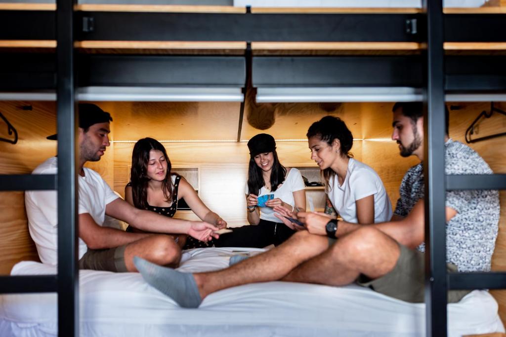 a group of people sitting on a bunk bed at GiG Capsule Hostel in Ericeira