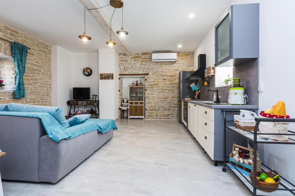 a kitchen and living room with a gray couch and a brick wall at Apartment Nostalgija, Benkovac in Benkovac