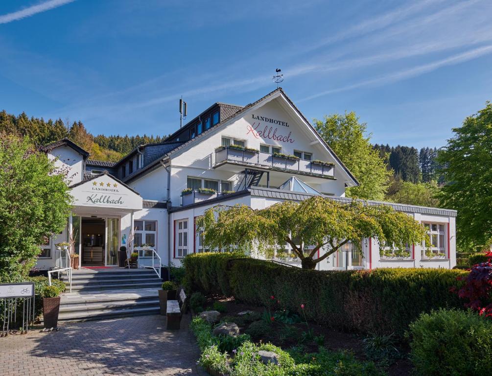 Un grand bâtiment blanc avec un escalier se trouve devant. dans l'établissement Landhotel Kallbach - 4 Sterne SUPERIOR, à Hürtgenwald