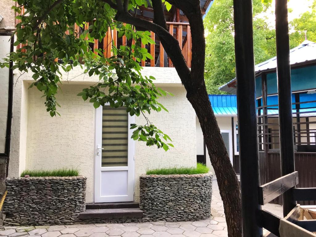 uma porta branca numa casa branca com plantas em Park Hostel Osh em Osh