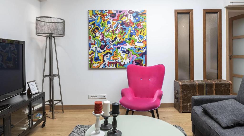 パリにある3ベッドルーム アパートメント ケ デ グラン オーギュスタンのピンクの椅子と絵画のあるリビングルーム