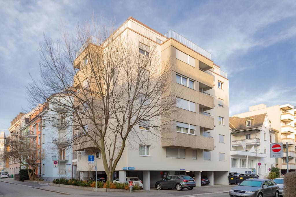 un edificio alto con un árbol delante de él en Swiss Star Wiedikon - Self Check-In, en Zúrich