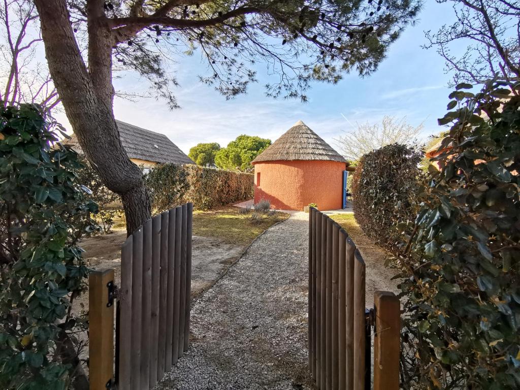 uma cerca de madeira com um portão e um edifício em Mas Rose des Vents em Le Barcarès