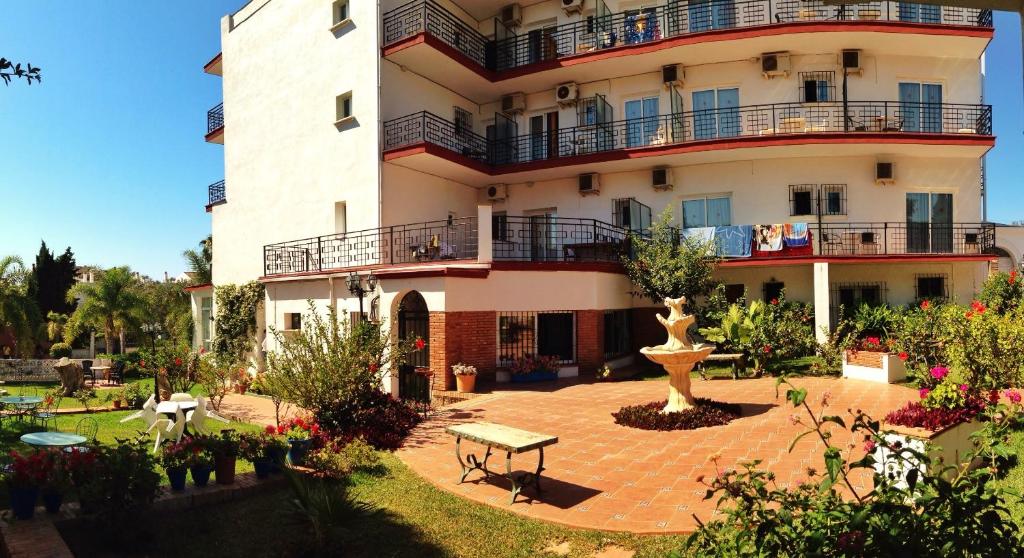 um grande edifício com um banco à frente em Hotel Carmen Teresa em Torremolinos