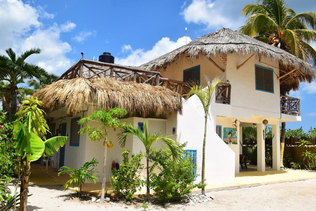 uma casa branca com telhado de palha e palmeiras em La Casa del Ritmo em El Cuyo