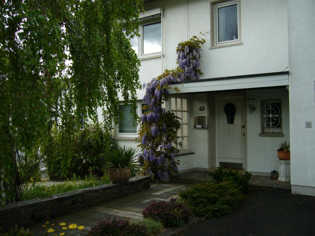 a white house with a wreath of purple flowers on it at Ferienwohnung am Ölsbach in Mudersbach