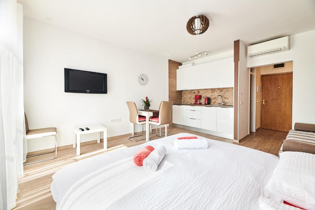 een witte slaapkamer met een wit bed en een keuken bij Studio apartman Lena in Umag