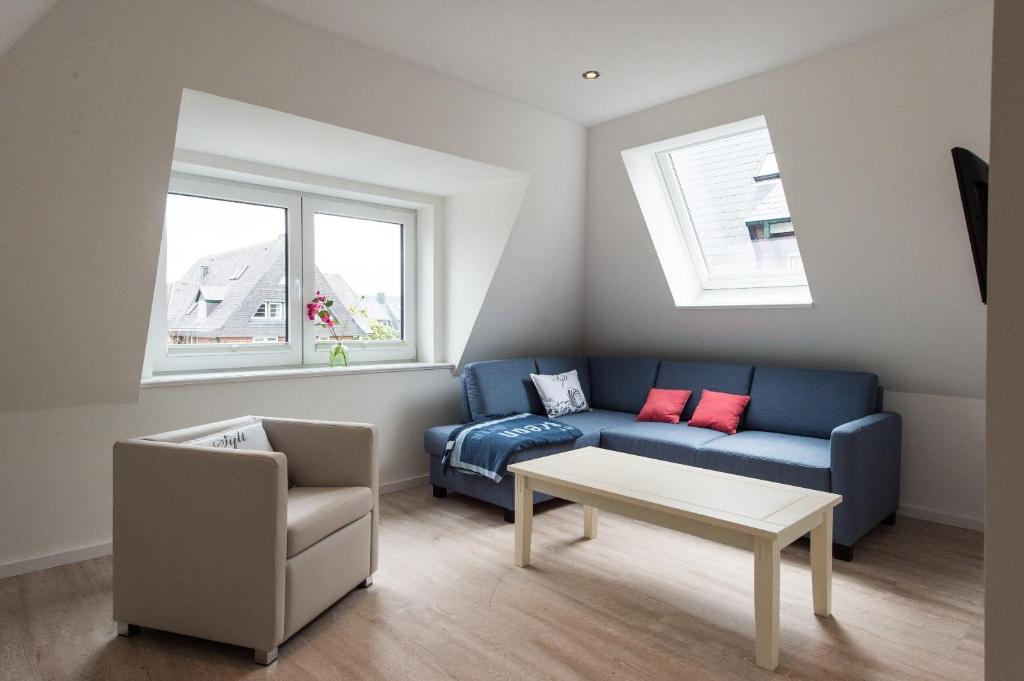Meeresbriese-Landhaus-Tadsen في فيسترلاند: غرفة معيشة مع أريكة زرقاء وكرسي