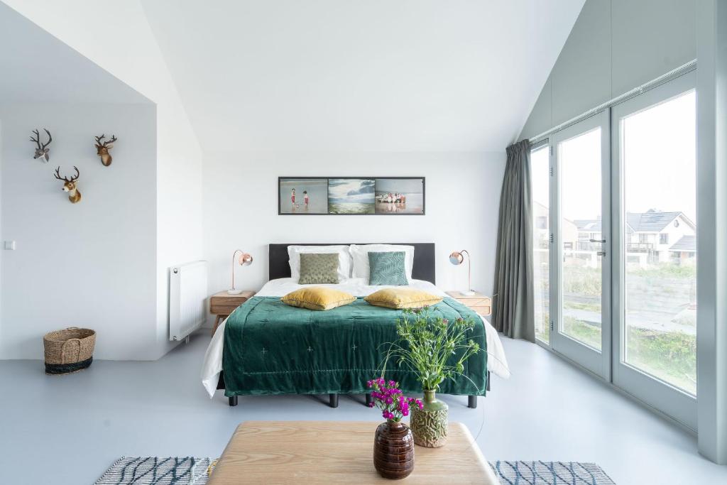 a white bedroom with a bed and a large window at Paulus Loot Zandvoort in Zandvoort