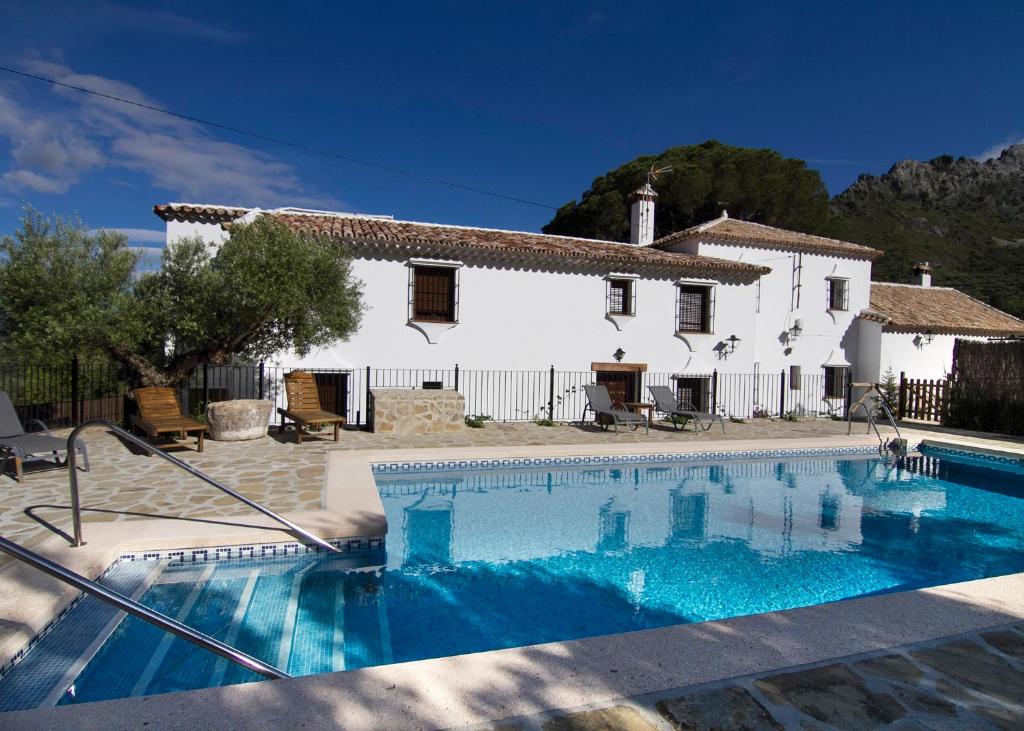 a villa with a swimming pool in front of a house at Casa Rural La Bodega in Grazalema