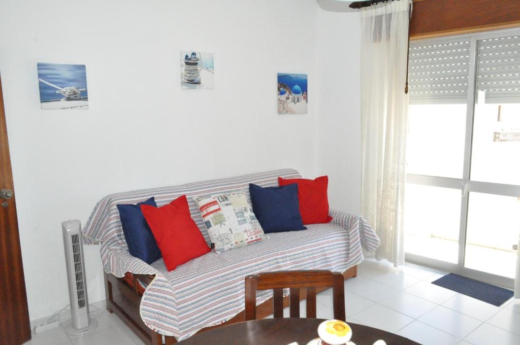 sala de estar con sofá y almohadas rojas y azules en Apartamento do Mar, en Armação de Pêra