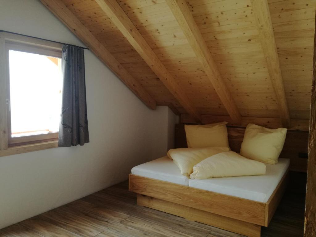 Bett in einem Zimmer mit Holzdecke in der Unterkunft Wieser Hütte in Stockenboi