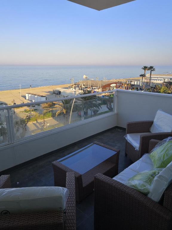een balkon met stoelen en tafels en uitzicht op het strand bij infinito in Alba Adriatica