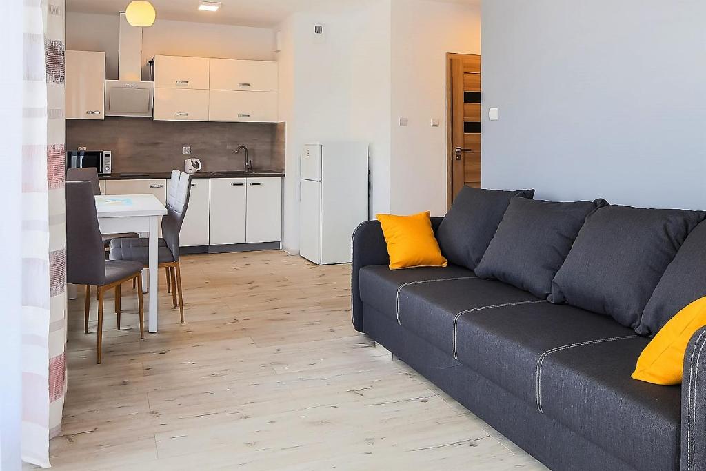 a living room with a couch and a kitchen at Apartament Bursztyn in Kołobrzeg