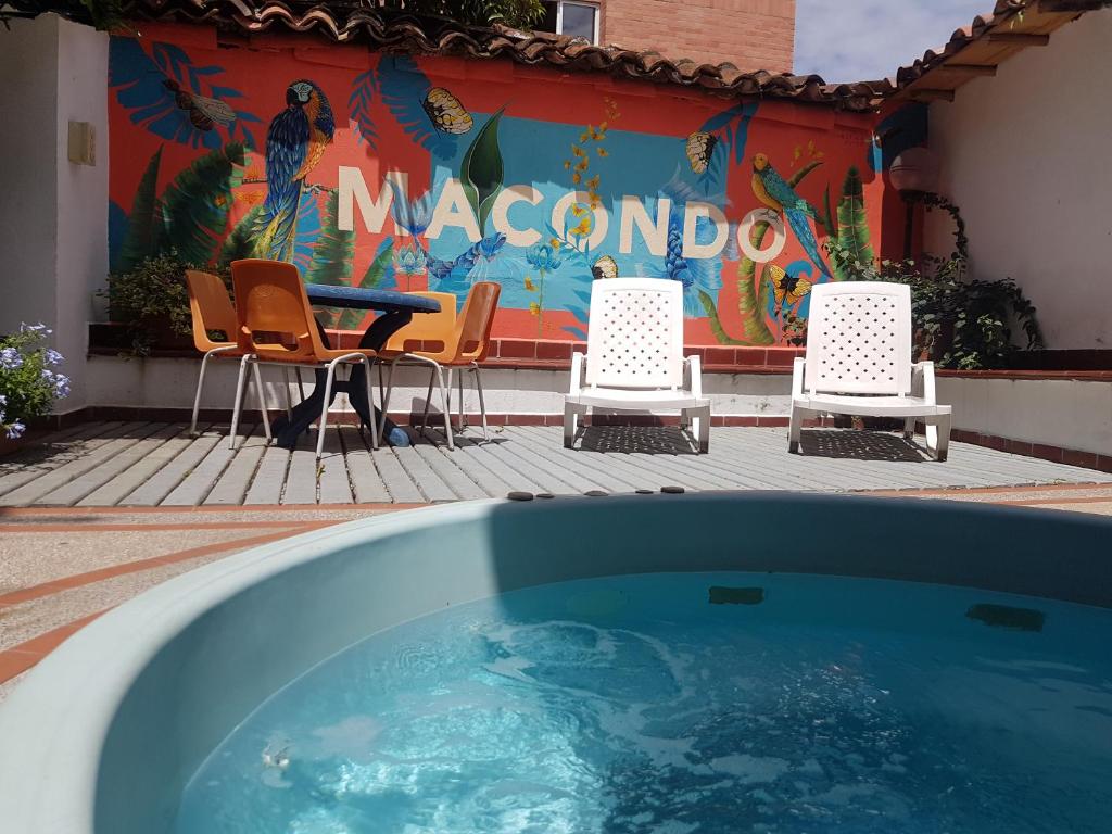 a pool with chairs and a table in front of a mural at Macondo Hostel in San Gil