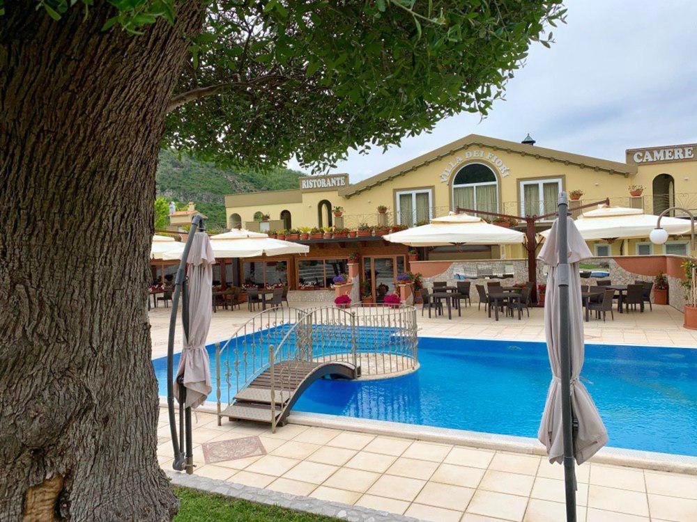 un hotel con una piscina con sombrillas junto a un árbol en Villa Dei Fiori, en Montoro Inferiore