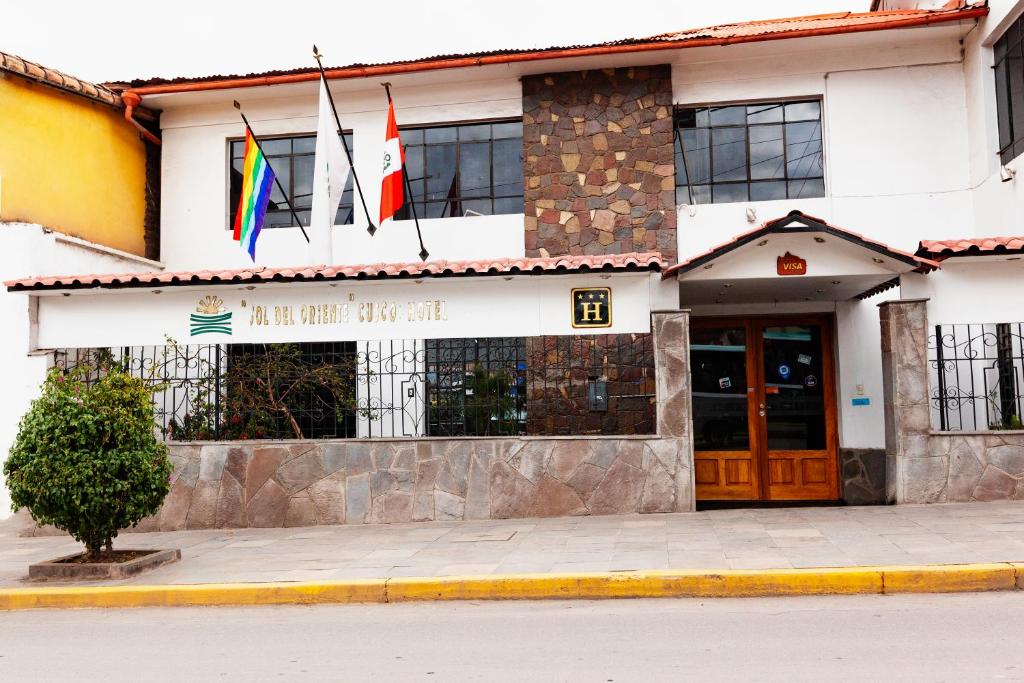 un edificio con dos banderas delante en Hotel Sol del Oriente Cusco, en Cusco