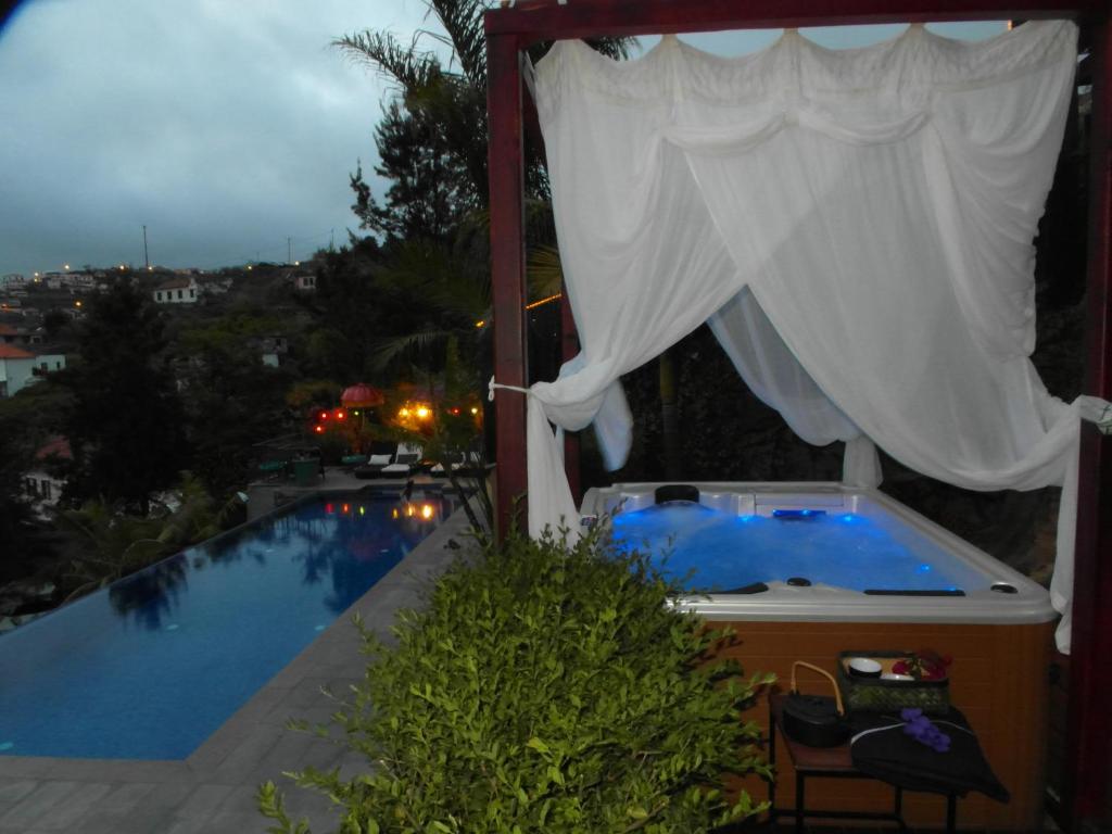 a hot tub in a gazebo next to a pool at Dazk Golden Estate in Ribeira Brava