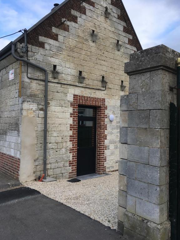 a brick building with a black door and a brick wall at Gite de sejour la grange de Théophile in Anzin-Saint-Aubin