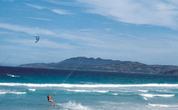 a person is flying a kite on the beach at Suítes Praia Do Foguete in Cabo Frio