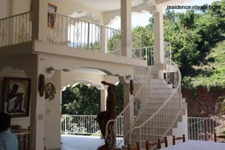 un escalier dans une maison avec une personne debout sur elle dans l'établissement Residence Royale Hôtel, à Cap-Haïtien