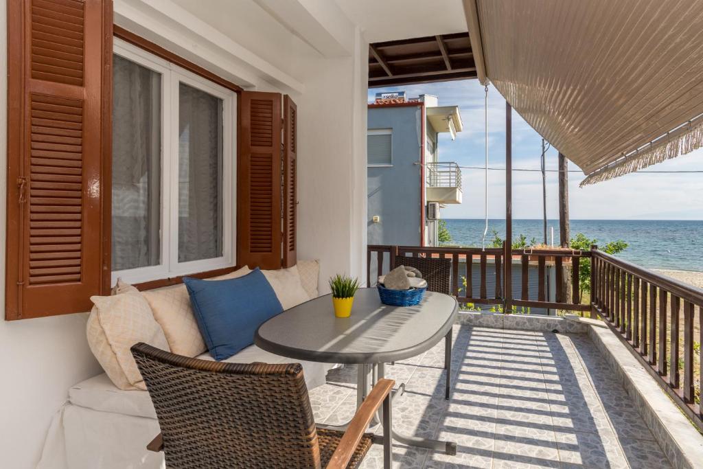 a patio with a table and chairs and the ocean at Chalkidiki Beachfront Apartment in Nea Irakleia
