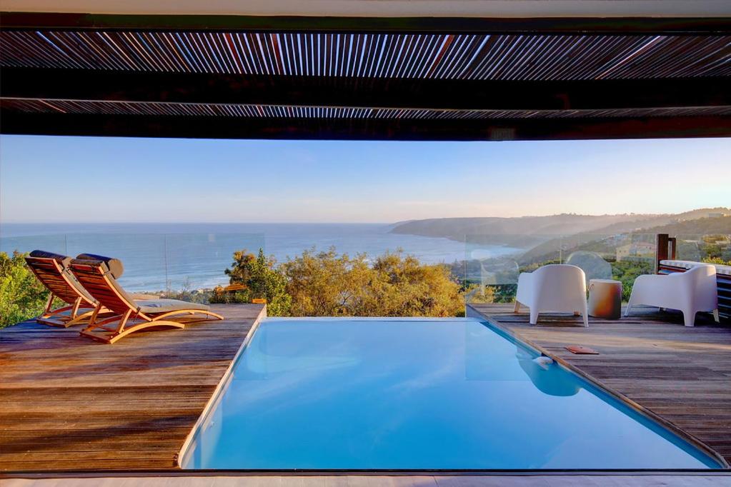 a pool with chairs and a view of the ocean at Talk in Wilderness