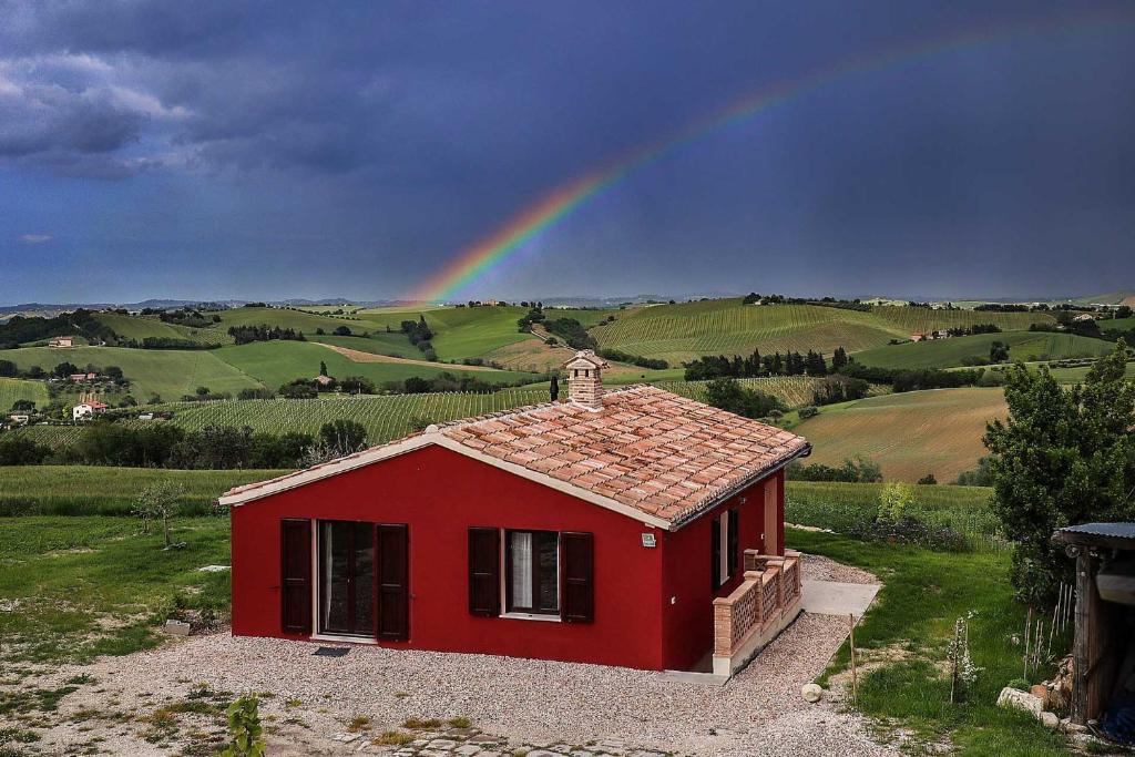 a red house with a rainbow in the background at La Chioccia in Serra deʼ Conti