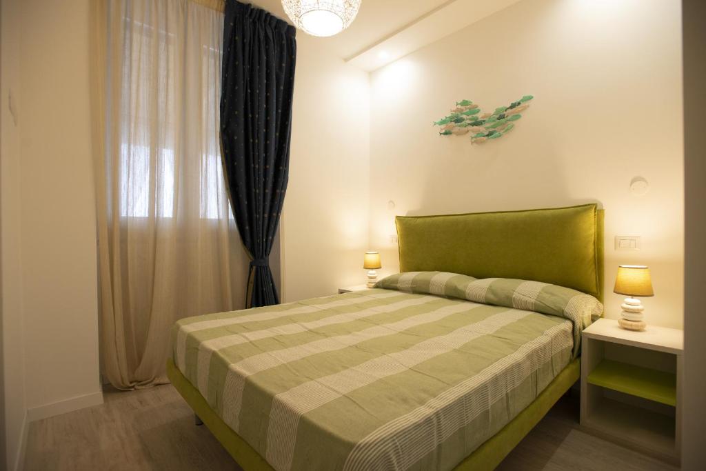 een slaapkamer met een groen bed en een raam bij Appartamento Roberto House in Fertilia