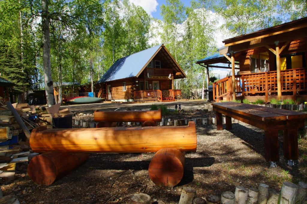Sven's Basecamp Hostel في فيربانكس: كابينة خشبية مع طاولة ومقعد خشبي