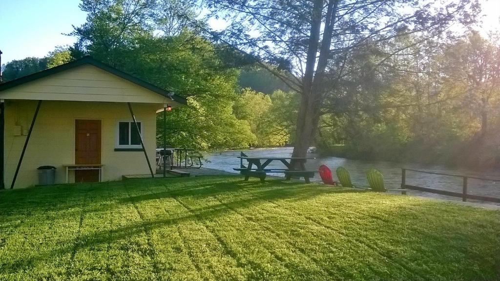 una casa con una mesa de picnic y sillas en el césped en Riverbend Lodging en Bryson City