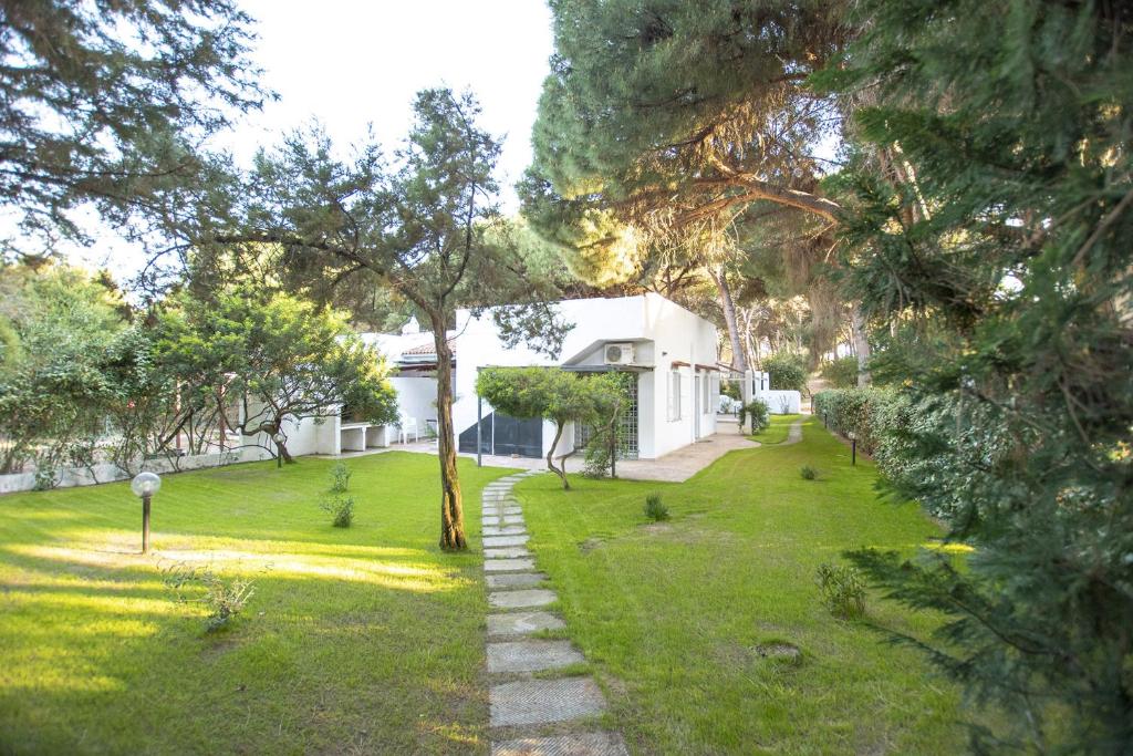 a yard with a white house and trees at Villa Eucalipto in Valledoria