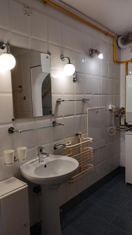 ein Bad mit einem Waschbecken und einem Spiegel in der Unterkunft Mandarynkowy in Dębki