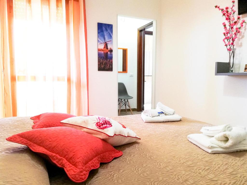 una camera da letto con un letto con cuscini rossi e uno specchio di A Due Passi Dal Molino a Valderice