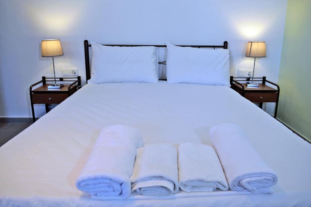 una camera da letto con un letto bianco e asciugamani di Le Case di Olga a Lygia