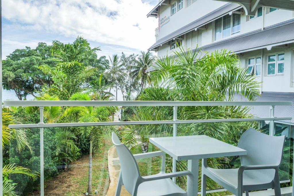 a balcony with a table and chairs in front of a building at Hotel Beaurivage in Noumea