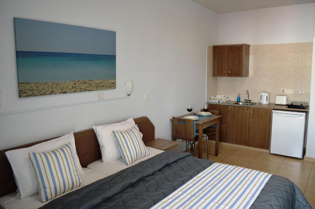 a bedroom with a bed and a kitchen with a beach at Millie's Apartments in Ayia Napa