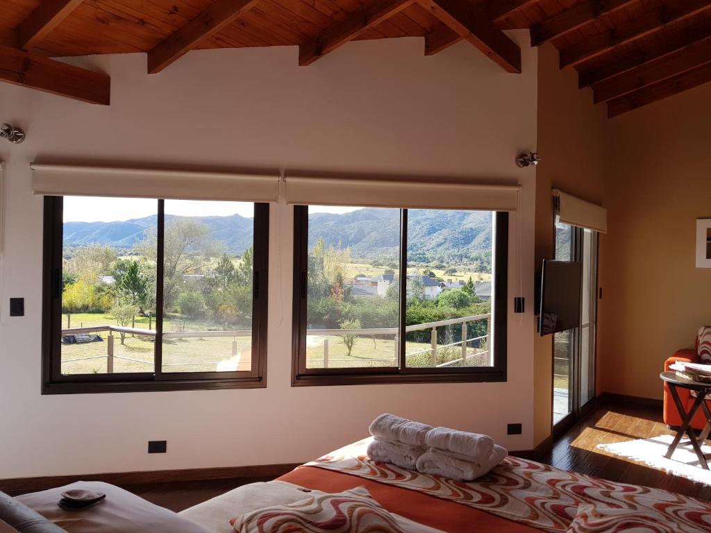 a bedroom with a large window with mountains in the background at La Macarena Suites in Villa General Belgrano