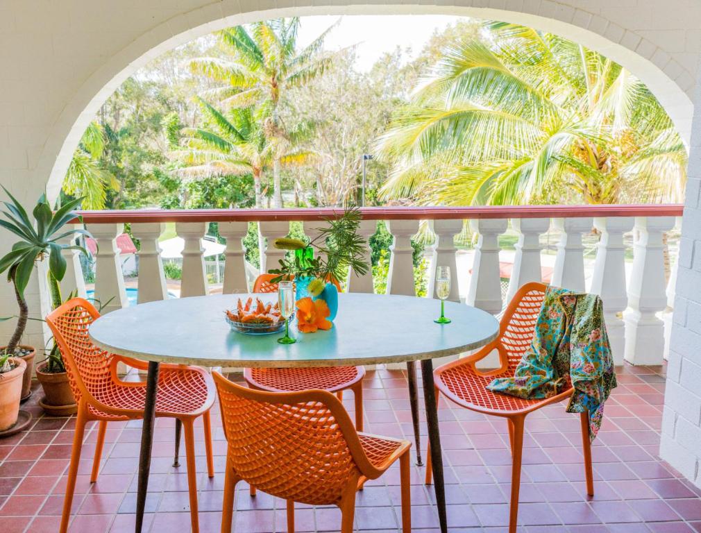 a table and chairs on a balcony with palm trees at 12 The Islander Resort in Point Lookout